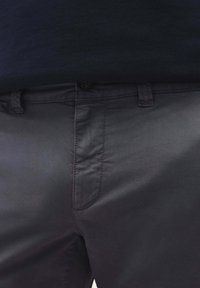 Mørkegrå bomulds-chinos med en glat tekstur, der har en knaplukning i taljen, bæltesløjfer og sidelommer.