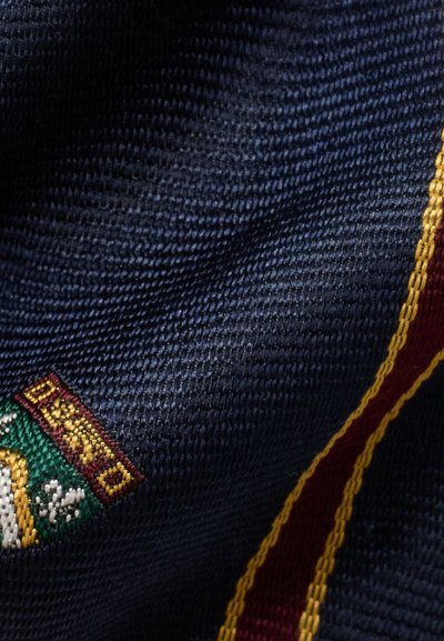 Navy scarf featuring a textured fabric, with a green and burgundy embroidered crest and a burgundy stripe along one edge.