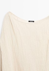 Kremowy, pofałdowany top z tkaniny z szerokim dekoltem i małą czarną metką Massimo Dutti przyszytą wewnątrz kołnierza.