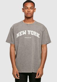 Grijs oversized t-shirt met "NEW YORK" in grote witte letters. Katoenen materiaal, ronde hals, korte mouwen en een ontspannen pasvorm.
