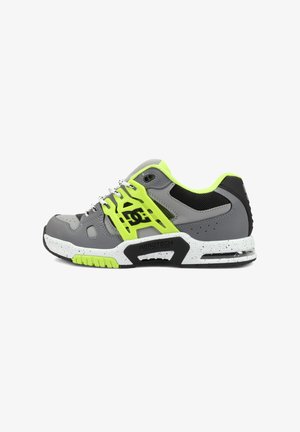 Pantof sport gri și galben neon cu plasă neagră, talpă albă cu pete și logo "DC" pe lateral, cu detaliu sistem de ventilație.