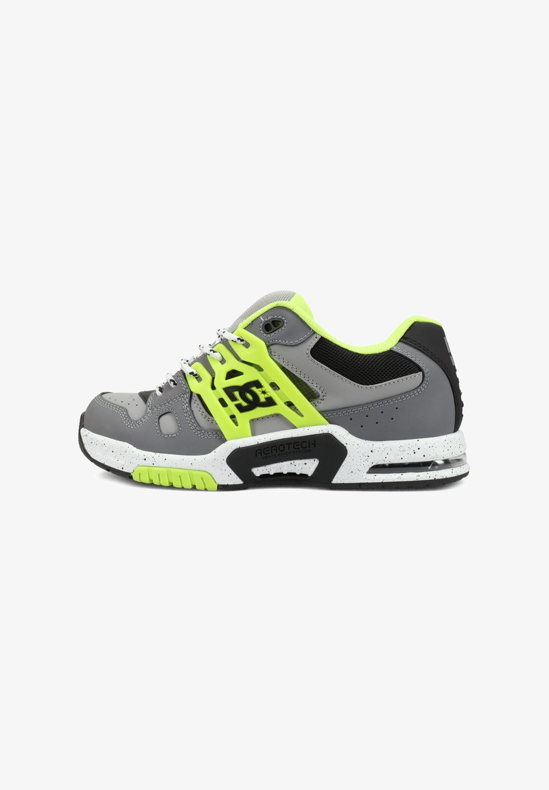 Baskets de sport grises et jaune néon avec un mesh noir, une semelle blanche mouchetée, et le logo "DC" sur le côté avec un détail de système de ventilation.