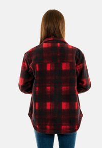 Chaqueta de forro polar a cuadros rojos y negros con cuello de solapa y dos bolsillos laterales, que presenta un ajuste relajado y un dobladillo ligeramente redondeado.