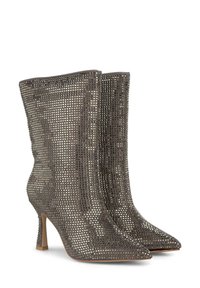 Metalowe botki na obcasie sięgające kostki z ostrym noskiem, z wzorem siatkowym i teksturowaną powierzchnią. Kolor srebrny z błyszczącym wykończeniem.