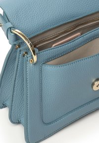 Borsa a mano in pelle color azzurro chiaro con finitura testurizzata, dettagli in metallo dorato, due scomparti e una tasca con cerniera.