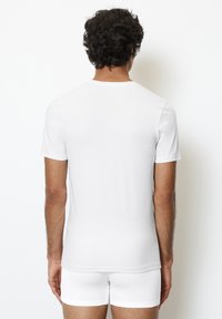 Witte T-shirt met korte mouwen, gemaakt van gladde stof, slim fit ontwerp, effen textuur, geknipt tot aan de taille, gedragen met bijpassende witte shorts.