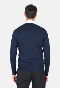 Maglione blu navy con maniche lunghe, collo rotondo e polsini e orlo a coste. Tessuto a maglia liscio, design aderente, dettaglio di cuciture visibili.