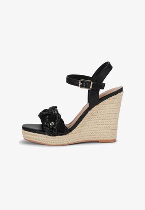 Schwarze Wedge-Sandale mit einem geflochtenen Textilobermaterial, verstellbarem Knöchelriemen und einer gewebten Jute-Plattform. Glattes Lederfußbett, rutschfeste Sohle.