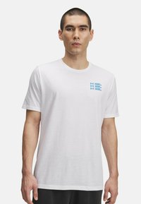 Balta kokvilnas T-krekls ar īsām piedurknēm. Zila uzraksta "UNDER ARMOUR" drukājums kreisajā krūtīs. Klasiska apaļa kakla izgriezums.