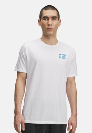 Camiseta de algodón blanca con mangas cortas. Texto azul "UNDER ARMOUR" impreso en el área del pecho izquierdo. Cuello redondo clásico.