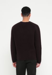 Σκούρο μωβ πλεκτό πουλόβερ με στρογγυλή λαιμόκοψη, μακριά μανίκια και χαλαρή εφαρμογή, διαθέτει υφαντό ύφασμα και διακριτές ραφές.