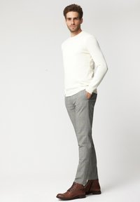 Biała, długosleeve'owa koszulka dzianinowa w połączeniu z szarymi, w kratkę, slim-fit spodniami oraz brązowymi skórzanymi butami na sznurowadła, z bocznymi kieszeniami.