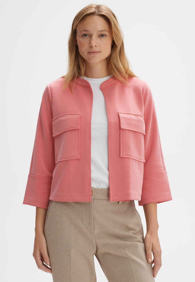Rosa kurz geschnittene Jacke mit rundem Ausschnitt, zwei Fronttaschen und Dreiviertelärmeln, aus glattem Stoff gefertigt.