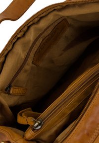 Braune Lederhandtasche mit einem glatten Innenfutter, Stoffauskleidung, mehreren Taschen und einem sichtbaren Reißverschluss für einen sicheren Verschluss.