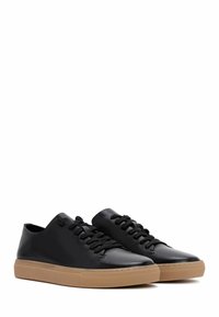 Sneaker in pelle nera con lacci neri e suola in gomma. Punta arrotondata, design low-top e dettagli di cuciture minime.