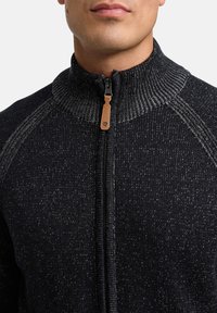 Czarny dziany sweter na zamek z wysokim kołnierzem, z teksturowanym wzorem i skórzanym detalem przy suwaku.