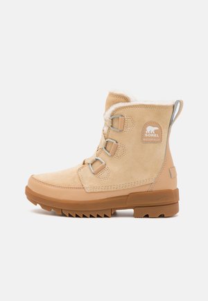 Bež veekindel nubukking, millel on kunstkarusnaha vooder, metallkinnitused ja robustne kummist tald, millel on sooneline muster haardevuse tagamiseks.