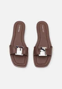 Bruna slidesandaler med fyrkantig tå, slät syntetisk överdel, med en stor metallspänne som accent och vadderad innersula.