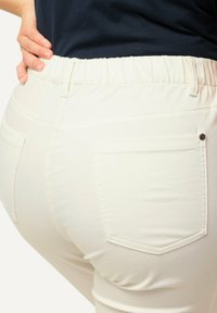 Witte katoenmix broek met een elastische tailleband, voorzien van twee achterzakken, gestikte details en een gladde textuur.