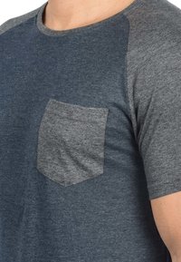 Sivi i tamnoplavni kratki rukavi T-shirt s rundastim izrezom i teksturiranom sivom džepom na lijevoj strani prsa. Mekana tkanina s suptilnim uzorkom.