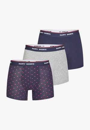 Tres pares de calzoncillos boxer para hombre: uno con fondo navy y patrón de corazones rojos, otro en navy sólido, y otro en gris jaspeado, todos con cinturillas elásticas.