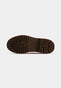Sola de bota Timberland em borracha castanha com ranhuras profundas, padrões hexagonais e em forma de estrela, apresentando detalhes do logótipo em relevo.