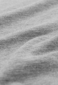 Hellgrauer Stoff mit einer weichen Textur, der subtile Tonvariationen und eine leicht gerippte Oberfläche aufweist, in sanften Falten angeordnet.