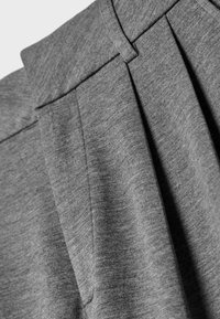 Szary plisowany materiał prezentujący gładką teksturę, lekko błyszczące wykończenie oraz dopasowany pas z detalami w postaci stębnowania.