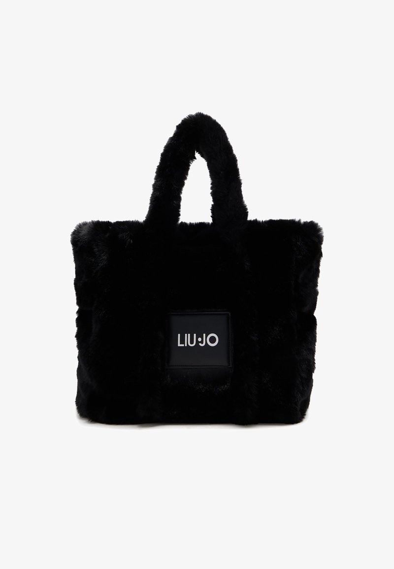 Borsa a spalla in pelliccia sintetica nera con doppio manico corto, forma rettangolare e una toppa con logo su un pannello nero liscio.