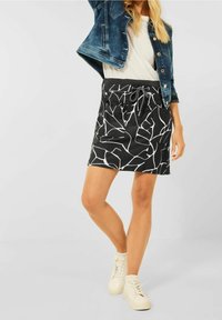 Černá sukně s bílým abstraktním vzorem, elastický pas, detaily se šňůrkou a postranními kapsami. Nosit s džínovou bundou a teniskami.
