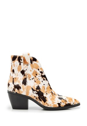 Ankle-height boot with a block heel, featuring a tan, white, and black cowhide pattern and a pull tab on the side.