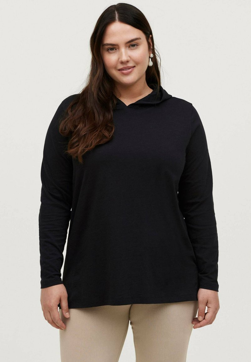 Sort langærmet hættebluse med en rund halsudskæring og afslappet pasform, lavet af blødt stof, båret med beige bukser. Minimalistisk design.