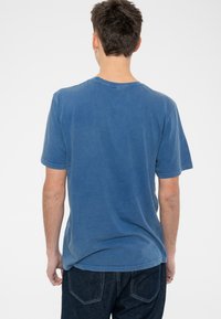 Blue cotton t-shirt with a relaxed fit, short sleeves, and a rounded neckline. Features a washed texture and stitch detailing at the hem.