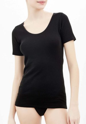 T-shirt nera a maniche corte in tessuto morbido con scollatura a girocollo, design aderente e trama liscia. Indossata con un capo inferiore nero abbinato.