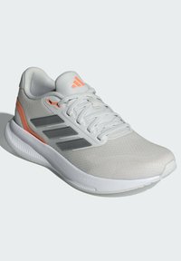 Hellgrauer Sportschuh mit weißer Sohle, Mesh-Obermaterial, drei dunkelgrauen Streifen und orangefarbenen Akzenten an den Seiten und der Ferse. Cloudfoam-Branding sichtbar.