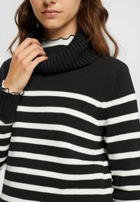 Schwarz-weißer gestreifter Pullover mit einem gerippten Rollkragen. Verfügt über eine dicke Strickstruktur und enganliegende Bündchen, die abwechselnd breite Streifen präsentieren.