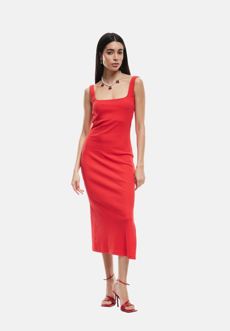 Robe midi rouge côtelée avec décolleté carré et coupe ajustée, dotée d'un ourlet évasé. Associée à des talons à lanières rouges.