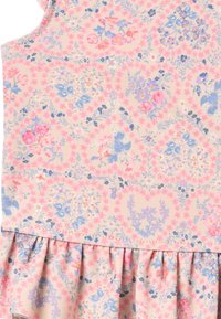 Tissu à motif floral aux couleurs pastel douces ; présente de petites roses et des feuilles, avec un volant froncé à l'ourlet. Léger et texturé.