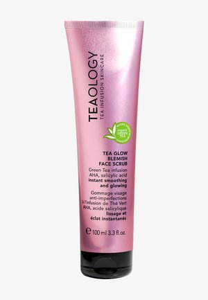 Teaology Tea Glow Blemish Face Scrub in een glanzende roze tube. Bevat tekst in zwart met groene accenten. Capaciteit van 100 ml, zwarte basis.