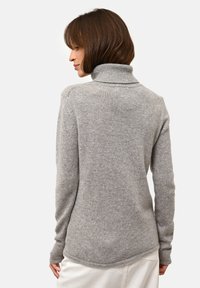 Grå polotröja med ribbat krage. Har en mjuk textur och rundad nederkant, designad för en figurnära silhuett.