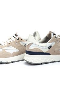 Zapatillas de ante beige con acentos de malla blanca, suela texturizada y detalles en azul marino, que cuentan con un collar acolchado y marca en negro.