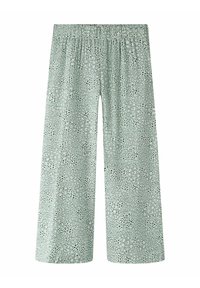 Pantalon ample vert clair avec motif de points noirs irréguliers et taille élastique, coupe jambes larges, vue de face sur fond blanc.