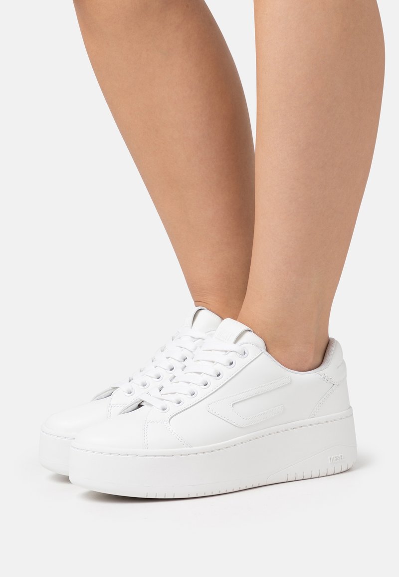 Valkoiset tasapohjakengät, joissa on sileä nahkapinta, pyöreä varvas ja nauhakiinnitys. Pehmeä sisävuori ja teksturoitu pohja.