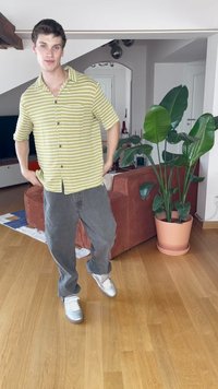 Majica s kratkim rukavima, u zeleno-bijelim prugama s dugmadi, uparena s sivo-baggy hlačama i srebrnim tenisicama. Unutarnji prostor s biljem.