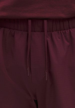 Bordó melegítők, elasztikus derékrésszel és húzózsinórral. Texturált anyagból készült, finom rácsmintával.