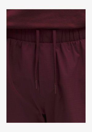 Bordó melegítők, elasztikus derékrésszel és húzózsinórral. Texturált anyagból készült, finom rácsmintával.