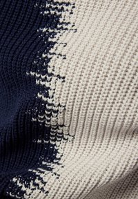 Strickdecke in Marineblau und Beige mit einem strukturierten Muster. Das Design zeichnet sich durch abwechselnd gerippte und glatte Bereiche aus, die visuelles Interesse schaffen.