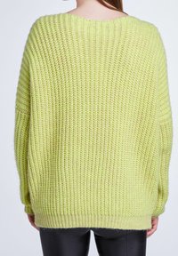 Pull oversize en maille vert clair, avec une texture épaisse, un col rond, des poignets et un ourlet côtelés.