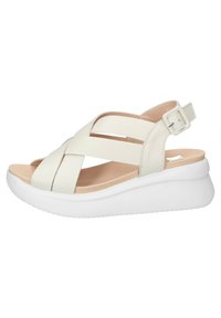 Le sandali bianchi da donna presentano un design con punta aperta, cinturino incrociato, fibbia per la caviglia regolabile e una suola a piattaforma spessa e bianca.