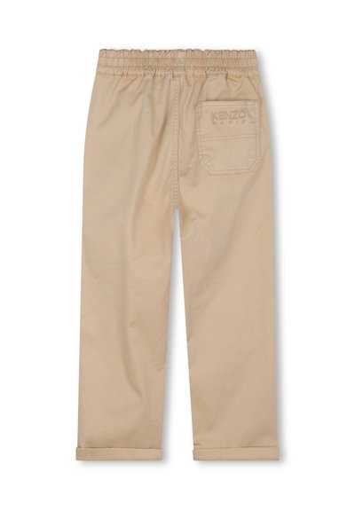Pantalon en coton beige avec taille élastique, jambes droites et ourlets retroussés. Il dispose d'une poche arrière unique avec un logo de marque en relief.